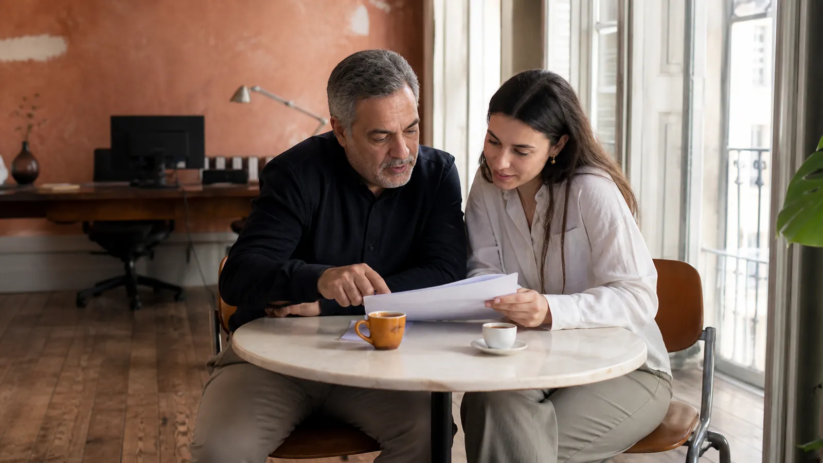 Payroll specialist and new hire reviewing a first payslip together in a Lisbon studio office