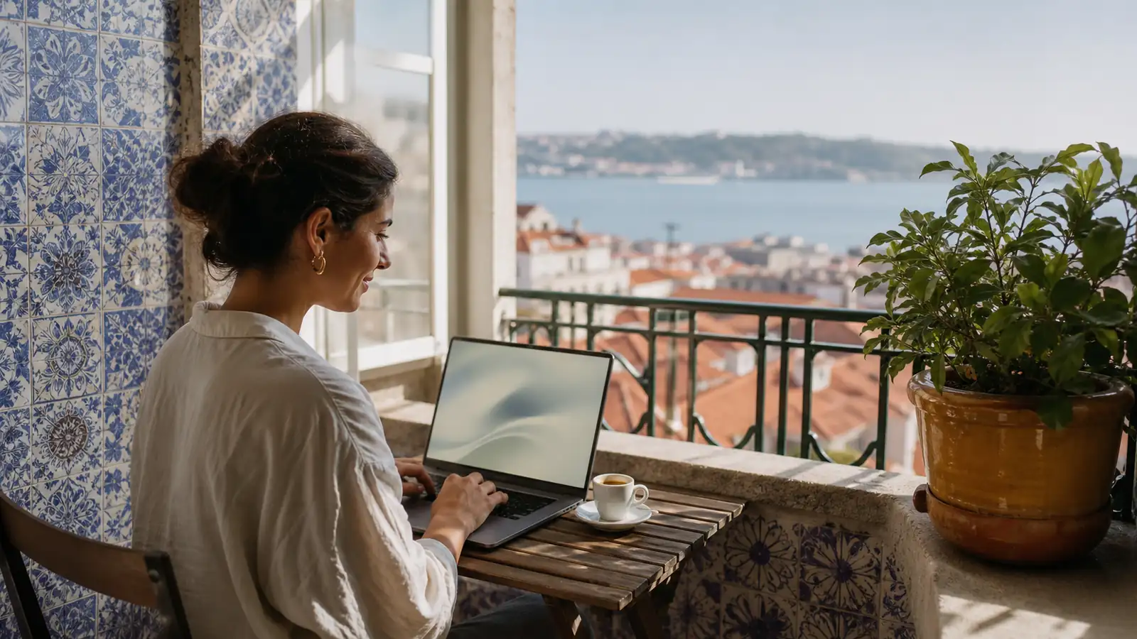 Professional working at a Lisbon balcony desk with azulejo-blue light and terracotta rooftops beyond
